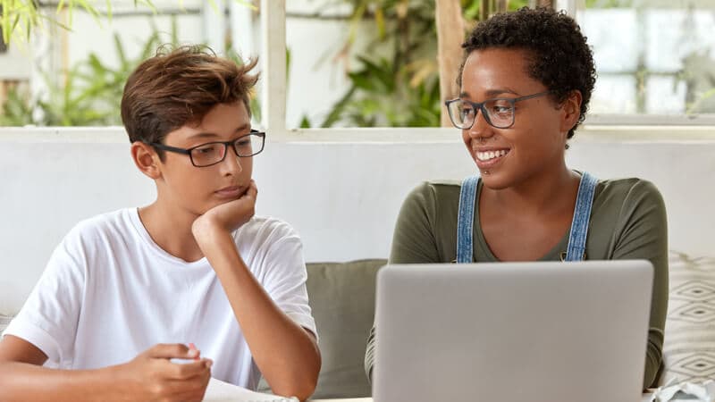 A teacher and a student smiling together over a laptop