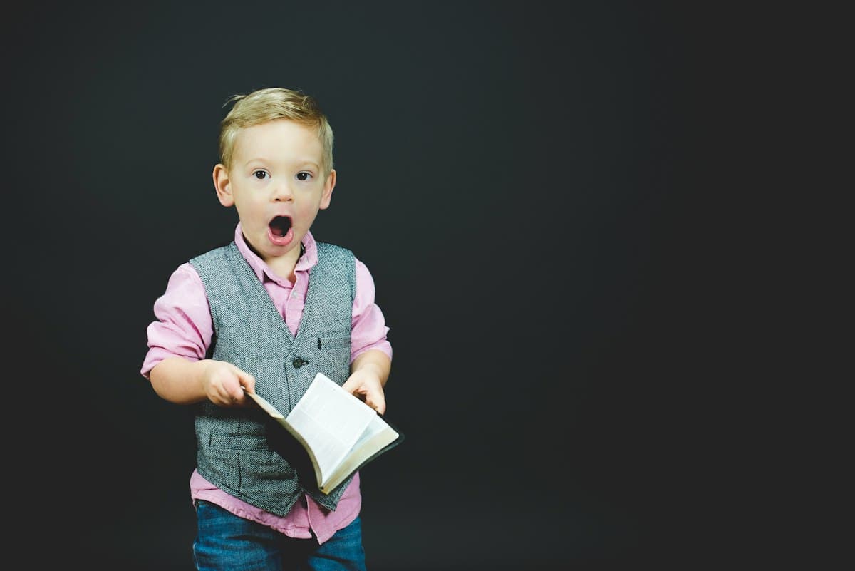 An expressive young boy holding a book