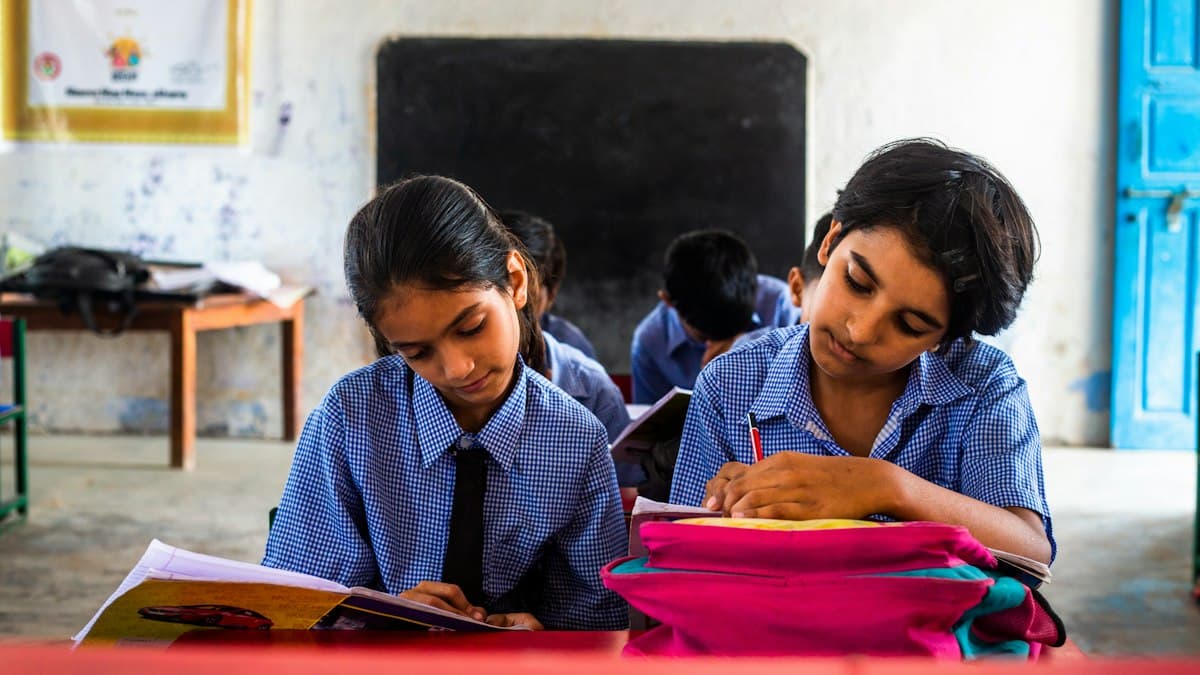 Two schoolgirls reading together at their desks