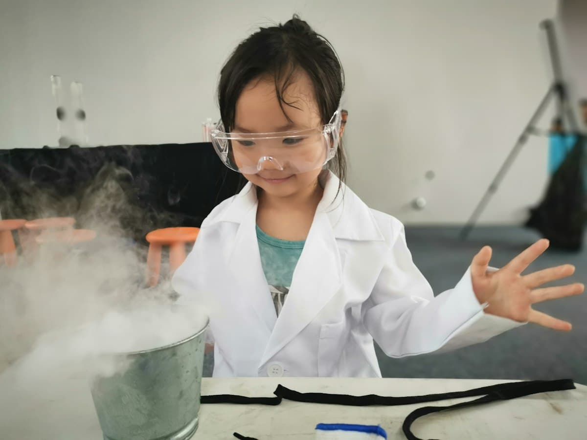 A girl in a lab coat and safety goggles doing a science experiment